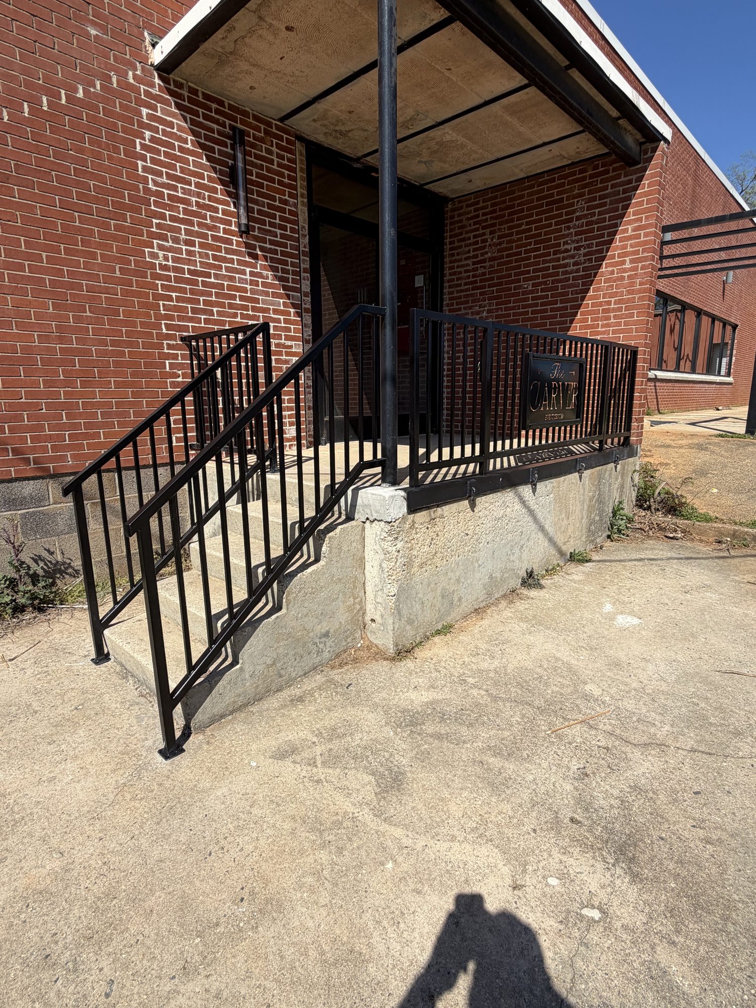 Carver project: white metal handrail along a porch with brick columns